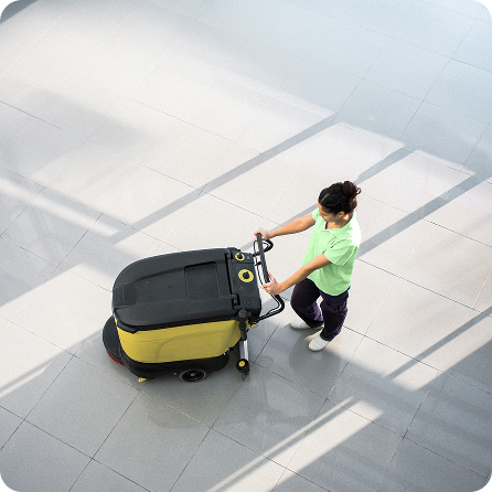 Cleaner using a floor scrubber machine indoors