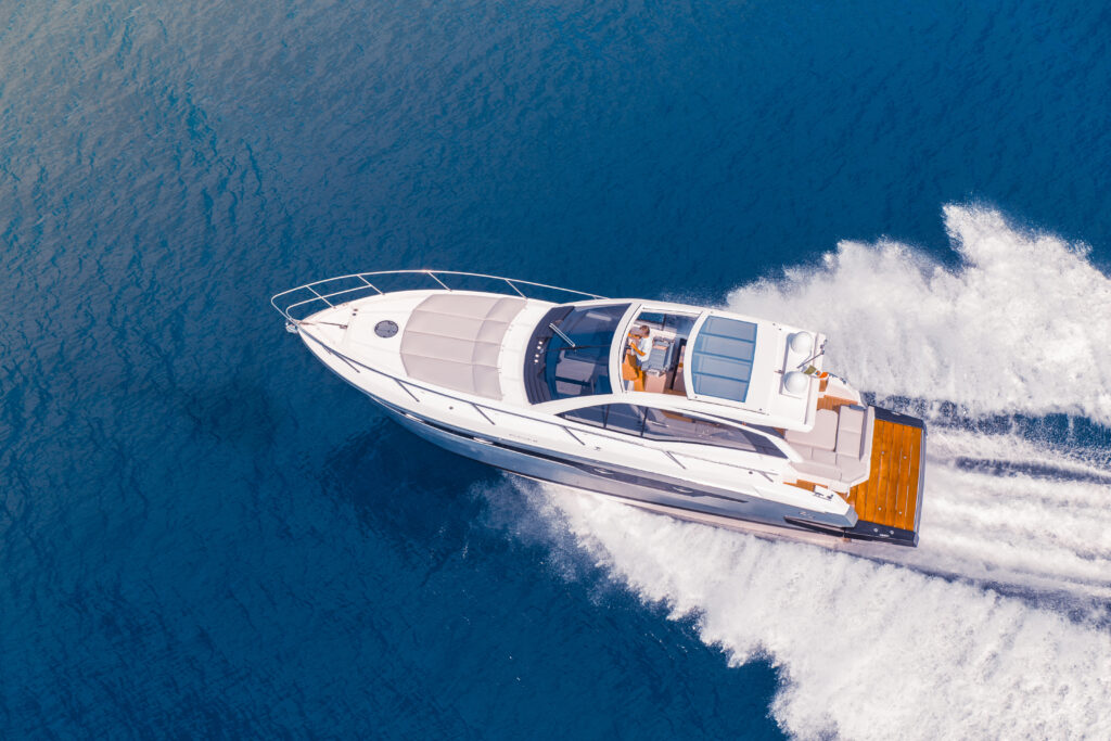 Luxury motor yacht speeding across open water, aerial view