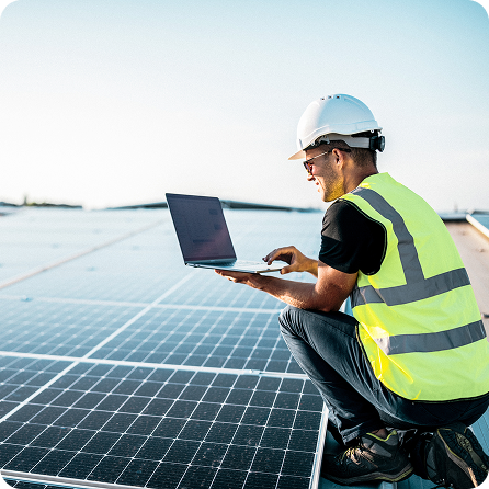 Solar engineer using a laptop during a rooftop solar panel installation