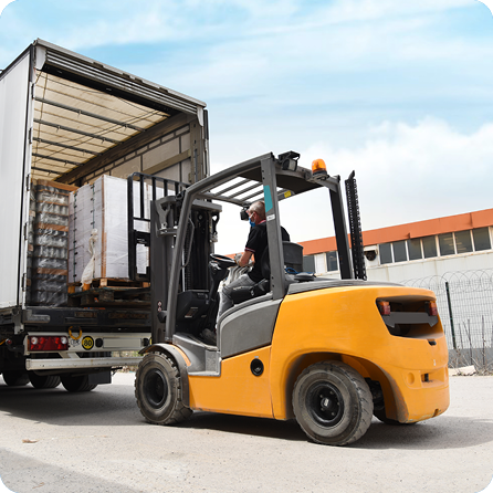 Forklift truck operator loading a delivery vehicle outside a warehouse