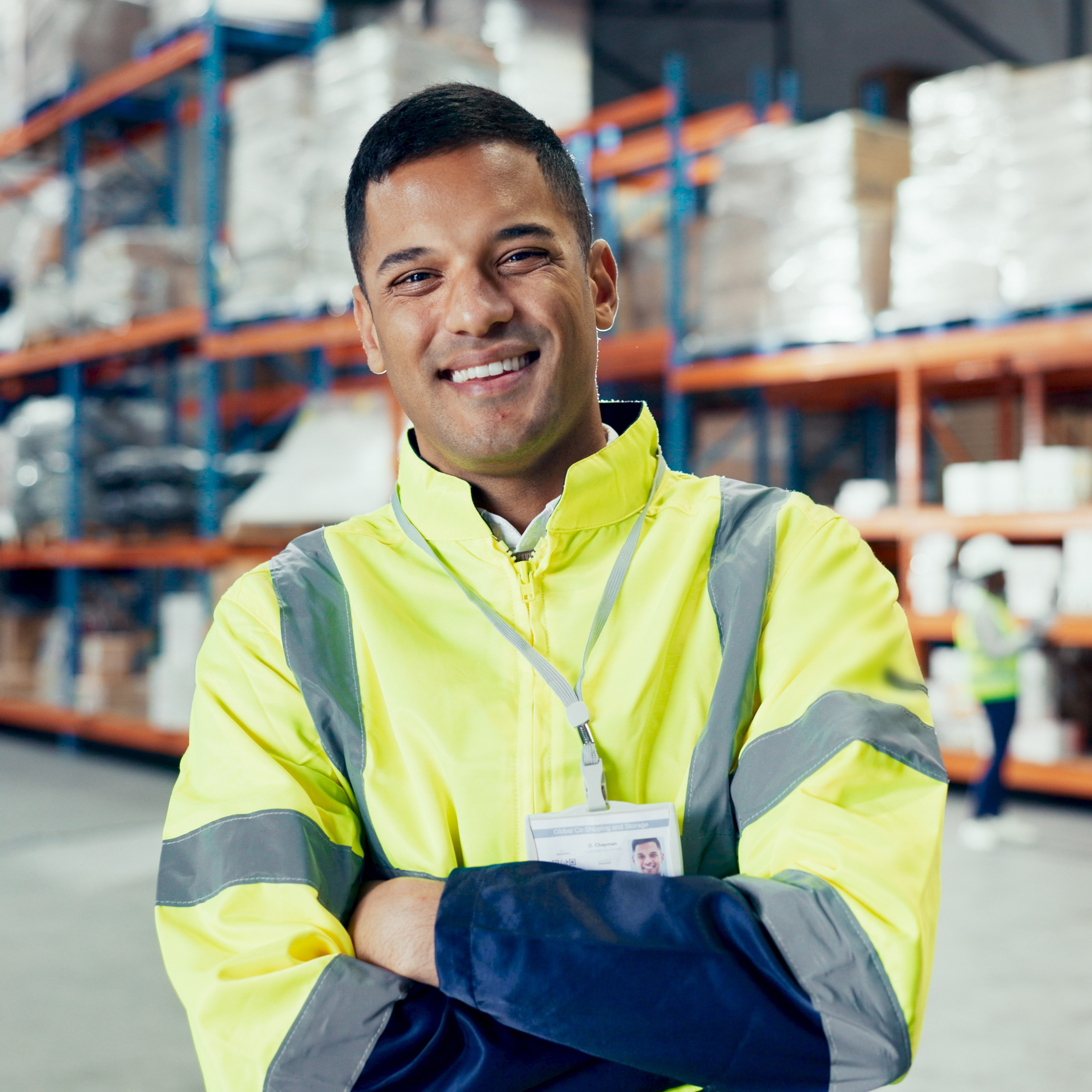 Smiling warehouse worker in high-vis jacket standing confidently in a distribution centre